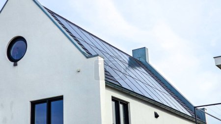 Téléchargez les photos : Maisons nouvellement construites avec des panneaux solaires noirs sur le toit contre un ciel ensoleillé Gros plan du nouveau bâtiment avec des panneaux solaires noirs. Zonnepanelen, Zonne energie, Traduction : Panneau solaire, Énergie solaire - en image libre de droit