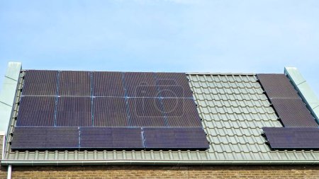 Téléchargez les photos : Maisons nouvellement construites avec des panneaux solaires noirs sur le toit contre un ciel ensoleillé Gros plan des maisons familiales modernes avec des panneaux solaires noirs. Zonnepanelen, Zonne energie, Traduction : Panneau solaire, Énergie solaire - en image libre de droit
