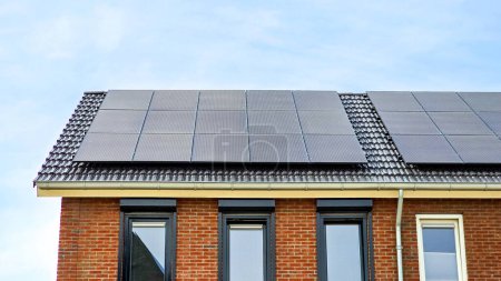 Photo for New house with black solar panels on the roof against a sunny sky Close up of new building with black solar panels. Zonnepanelen, Zonne energie, Translation: Solar panel, Sun Energy - Royalty Free Image