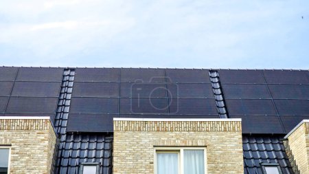 Téléchargez les photos : Maisons nouvellement construites avec des panneaux solaires noirs sur le toit au printemps, Gros plan du nouveau bâtiment avec des panneaux solaires noirs. Zonnepanelen, Zonne energie, Traduction : Panneau solaire, Énergie solaire - en image libre de droit