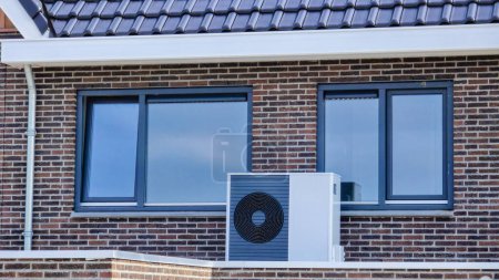 Foto de Unidad de bomba de calor de fuente de aire instalada al aire libre en una casa moderna con ladrillos en los Países Bajos, cálida pompa traducción bomba de calor de fuente de aire - Imagen libre de derechos
