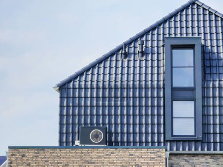 Luftquelle Wärmepumpe im Freien an einem modernen Haus mit Ziegeln in den Niederlanden im Frühjahr installiert, warme Pomp Translation Luftquelle Wärmepumpe, CO2-neutral