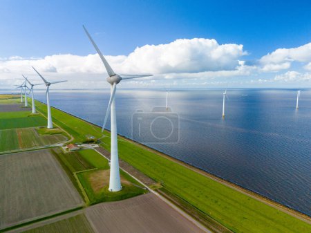 Téléchargez les photos : Un parc éolien génère de l'énergie propre au milieu d'un vaste lac hollandais, avec des rangées d'éoliennes tournant gracieusement sous le ciel printanier. Ijsselmeer éoliennes Noordoostpolder Pays-Bas - en image libre de droit