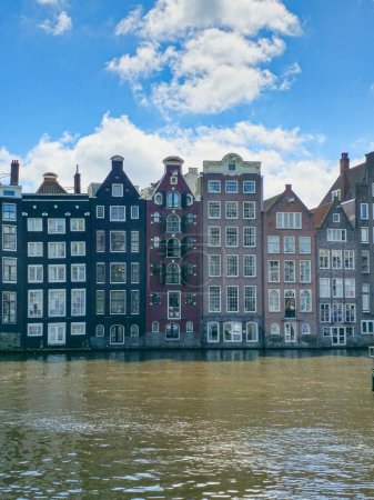 Foto de Una encantadora hilera de siluetas de edificios contra las tranquilas aguas, creando una pintoresca escena de arquitectura urbana que reúne la belleza natural. Amsterdam Países Bajos 21 abril 2024 - Imagen libre de derechos