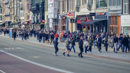 Foto de Ámsterdam Países Bajos 21 de abril de 2024, Una multitud diversa de personas camina rápidamente por una bulliciosa calle de la ciudad llena de edificios imponentes - Imagen libre de derechos