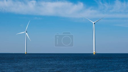 Foto de Dos aerogeneradores se alzan en medio del océano, aprovechando el poder del viento para generar energía renovable para la región holandesa de Flevoland. turbinas de molino de viento en el mar - Imagen libre de derechos