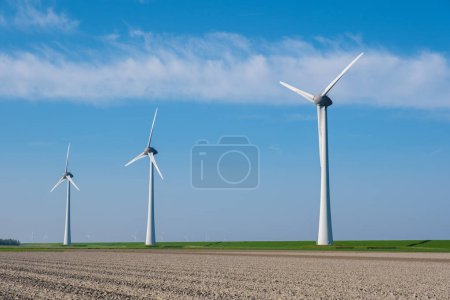Une majestueuse rangée d'éoliennes géantes tourne gracieusement dans un vaste champ du Flevoland néerlandais, exploitant la puissance du vent pour produire une énergie propre et durable. Transition énergétique 