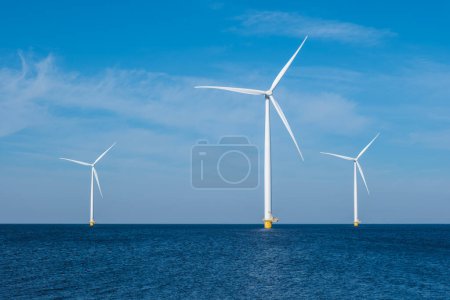 Foto de Un grupo de elegantes turbinas eólicas se alza en el océano en los Países Bajos Flevoland, aprovechando el poder del viento para generar energía renovable. Turbinas de molinos de viento en el mar, - Imagen libre de derechos