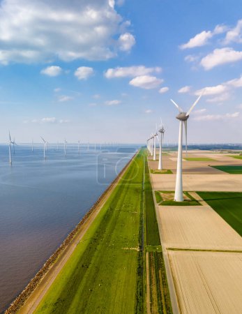Eine faszinierende Luftaufnahme einer Reihe majestätischer Windkraftanlagen, die sich anmutig in der weiten Landschaft von Flevoland, Niederlande, drehen.
