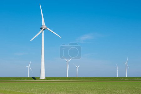 Un groupe d'éoliennes tourne gracieusement dans un vaste champ vert, exploitant la puissance du vent pour produire de l'énergie propre pour les Pays-Bas.