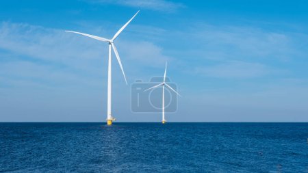 Zwei majestätische Windturbinen ragen in den riesigen Ozean, fangen die Kraft des Windes ein und erzeugen erneuerbare Energie für die Niederlande. Tag der Erde, Kopierraum