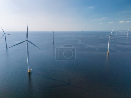 Eine Gruppe von Windmühlen mit Turbinenschaufeln schwebt friedlich auf den ruhigen Gewässern von Flevoland, Niederlande, und schafft eine harmonische und malerische Szenerie.