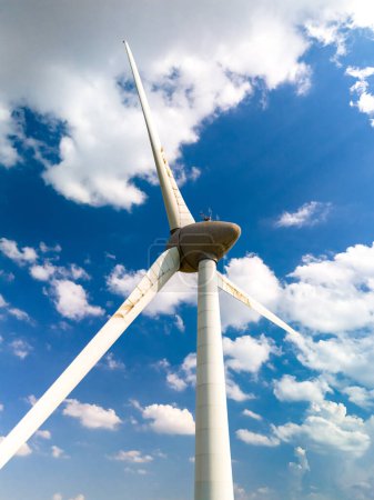 Foto de Un majestuoso aerogenerador se fija contra un cielo azul vibrante, girando con gracia, ya que aprovecha el poder del viento en los Países Bajos Flevoland. - Imagen libre de derechos
