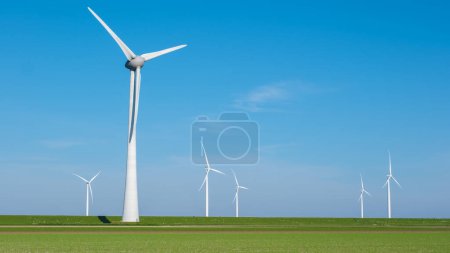 Un groupe d'éoliennes danse gracieusement dans un champ vert luxuriant sous le ciel bleu clair, exploitant la puissance du vent pour générer de l'énergie propre.
