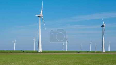 A serene field of vibrant green grass stretches out before us, dotted with a collection of majestic windmills spinning gracefully in the background.