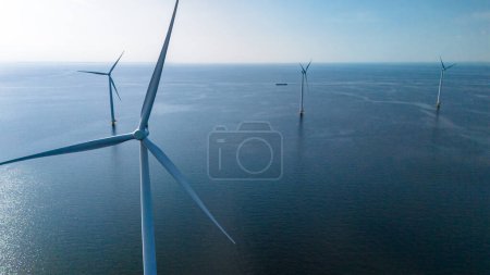 Eine Gruppe majestätischer Windräder steht hoch im Ozean, ihre Flügel drehen sich anmutig im Wind, um saubere, erneuerbare Energie zu erzeugen.