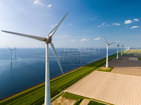 Eine Reihe hoch aufragender Windkraftanlagen steht stolz neben dem ruhigen Wasser von Flevoland in den Niederlanden.