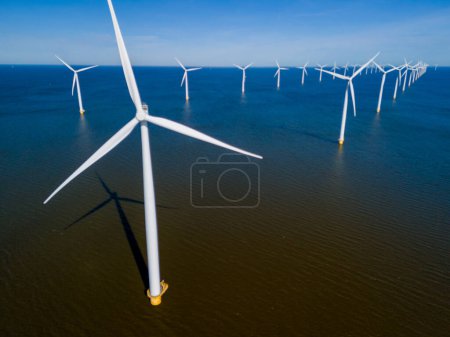Eine Gruppe majestätischer Windräder, die hoch im Ozean vor einem bewölkten Himmel stehen und die Kraft des Windes nutzen, um nachhaltige Energie zu erzeugen. Drohnen-Luftaufnahme von Windkraftanlagen 