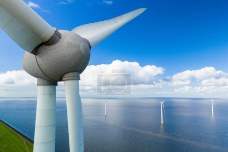 Foto de Una sola turbina eólica se encuentra alta en medio de un gran cuerpo de agua, aprovechando la energía del viento para generar electricidad en los Países Bajos Noordoostpolder, turbinas de molino de viento en el océano - Imagen libre de derechos