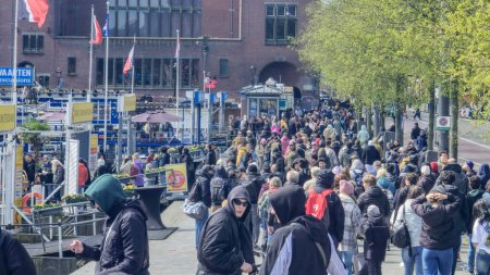 Téléchargez les photos : Amsterdam Pays-Bas 21 avril 2024, Une scène vibrante se déroule alors qu'un grand groupe d'individus divers se promène tranquillement dans une rue animée de la ville, créant un flux dynamique de mouvement et d'énergie. - en image libre de droit