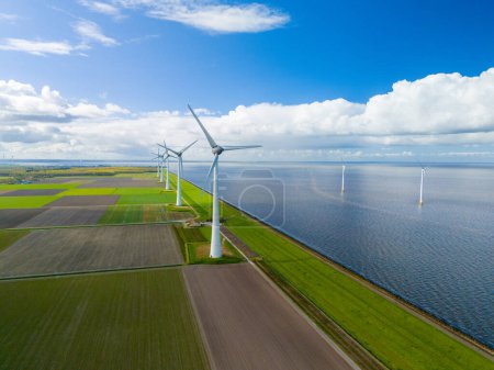 Ein faszinierendes Luftbild eines Windparks mit Reihen majestätischer Windturbinen, die sich anmutig in der Nähe des riesigen Ozeans drehen und die Energie der Windböen nutzen.