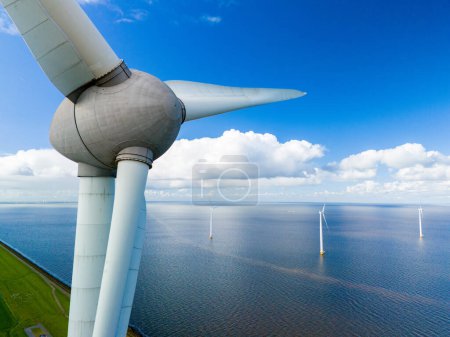 Foto de Una perspectiva aérea captura el movimiento agraciado de una turbina de viento de pie en la vasta extensión del océano. turbinas de molino de viento en los Países Bajos Noordoostpolder - Imagen libre de derechos