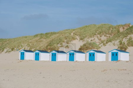 Eine bunte Reihe von Strandhütten steht stolz am Sandstrand von Texel, Niederlande, unter einem klaren blauen Himmel. Strand von De Koog Texel