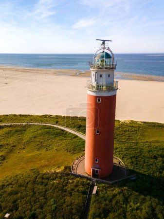 An aerial perspective of a historic lighthouse standing tall on the sandy shores of Texel, Netherlands, overlooking the vast expanse of the North Sea.