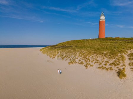 Ein majestätischer Leuchtturm steht hoch auf einem Sandstrand auf Texel und bietet Schiffen, die das Wasser befahren, Orientierung und Schutz..