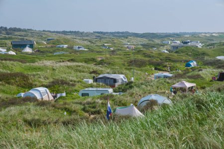 A group of tents nestled on a lush grassy hillside on the picturesque island of Texel in the Netherlands, offering a peaceful and idyllic retreat for outdoor adventurers.