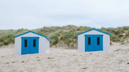 Zwei charmante Strandhütten mit leuchtend blauen Türen ragen inmitten der Sandstrände von Texel hervor und laden zum Entspannen und Genießen des Meerblicks ein. Strand von De Koog Texel