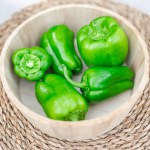 green and yellow peppers on a wooden background.