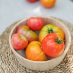fresh tomatoes in a basket on a wooden background