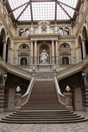Téléchargez les photos : Vienne, Autriche - 19 mars 2018 : Le bâtiment du ministère de la Justice à Vienne, Autriche. L'escalier central est décoré d'une statue de justice avec une épée à la main - en image libre de droit