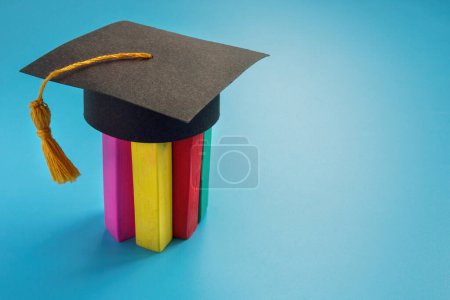 Photo for Inclusion and neurodiversity education. Colored crayons on which graduation cap is worn. - Royalty Free Image