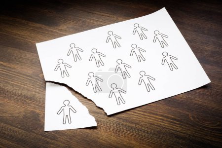 Photo for Disengaged Employees concept. Figures of people on sheet of paper and one is torn off. - Royalty Free Image