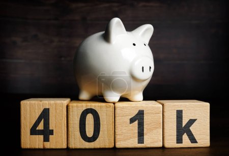 A Piggy bank on the wooden cubes with sign 401k. Retirement plan concept.