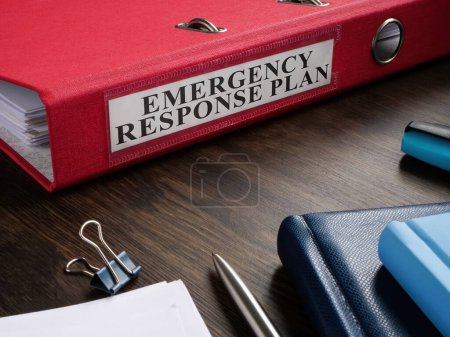 Una carpeta roja con plan de respuesta de emergencia en el escritorio.
