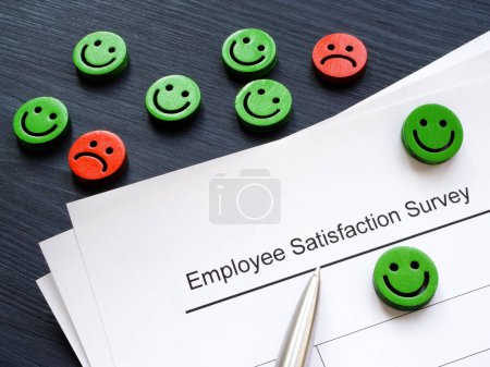 Emoticons und Papiere mit Umfrage zur Mitarbeiterzufriedenheit.
