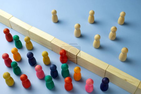 Photo for Diversity and immigration concept. Multi-colored figures are separated from wooden ones by a wall. - Royalty Free Image
