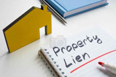 Property lien. Small house and writing in notebook.