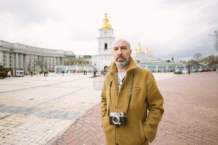 Photo for Handsome beard photographer makes pictures on film retro camera in the Kyiv city, Ukraine - Royalty Free Image