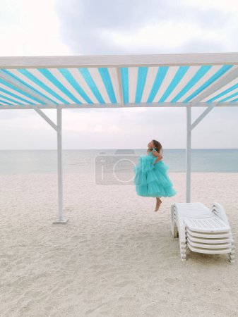 Foto de Niña en vestido de menta está saltando en la playa - Imagen libre de derechos