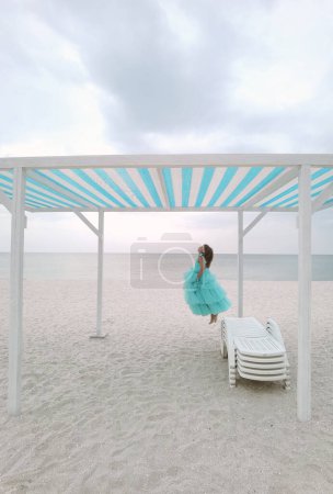Foto de Niña en vestido de menta está saltando en la playa - Imagen libre de derechos