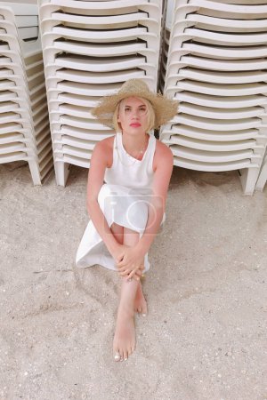 Téléchargez les photos : Portrait de femme boho portant un chapeau de paille et des vêtements d'été à la mode, posant sur la plage. Coucher ou lever du soleil. Détends-toi.. - en image libre de droit