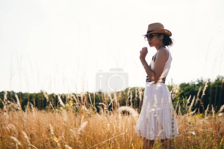 Foto de Retrato de mujer en luz dorada al atardecer en prado exterior. Primavera y estilo de vida veraniego. Bienestar y zen como actividad de meditación al aire libre. Amar la vida - Imagen libre de derechos