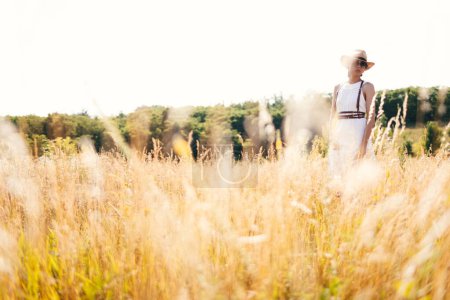 Foto de Hermosa chica en un vestido de lino en un campo de trigo. Vacaciones de verano, viajes. Bohemio, estilo hippie moderno. - Imagen libre de derechos