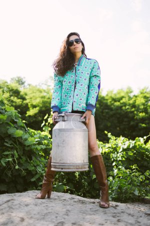 Téléchargez les photos : Jeune agricultrice à la mode posant à la caméra tout en tenant la boîte de lait. - en image libre de droit