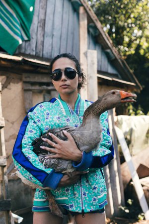 Photo for Fashionable young woman farmer holds goose - Royalty Free Image