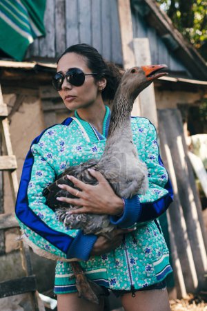 Foto de Joven agricultora de moda sostiene ganso - Imagen libre de derechos